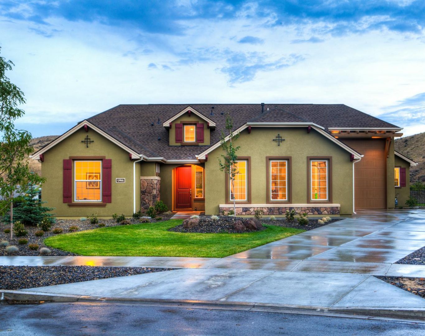Beautifully illuminated modern home exterior with a lush lawn and wet driveway in Boise, Idaho.