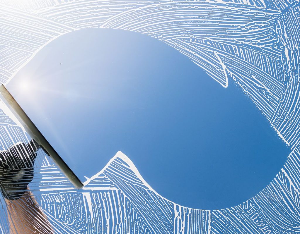 Technician performing eco-safe soft wash on house exterior